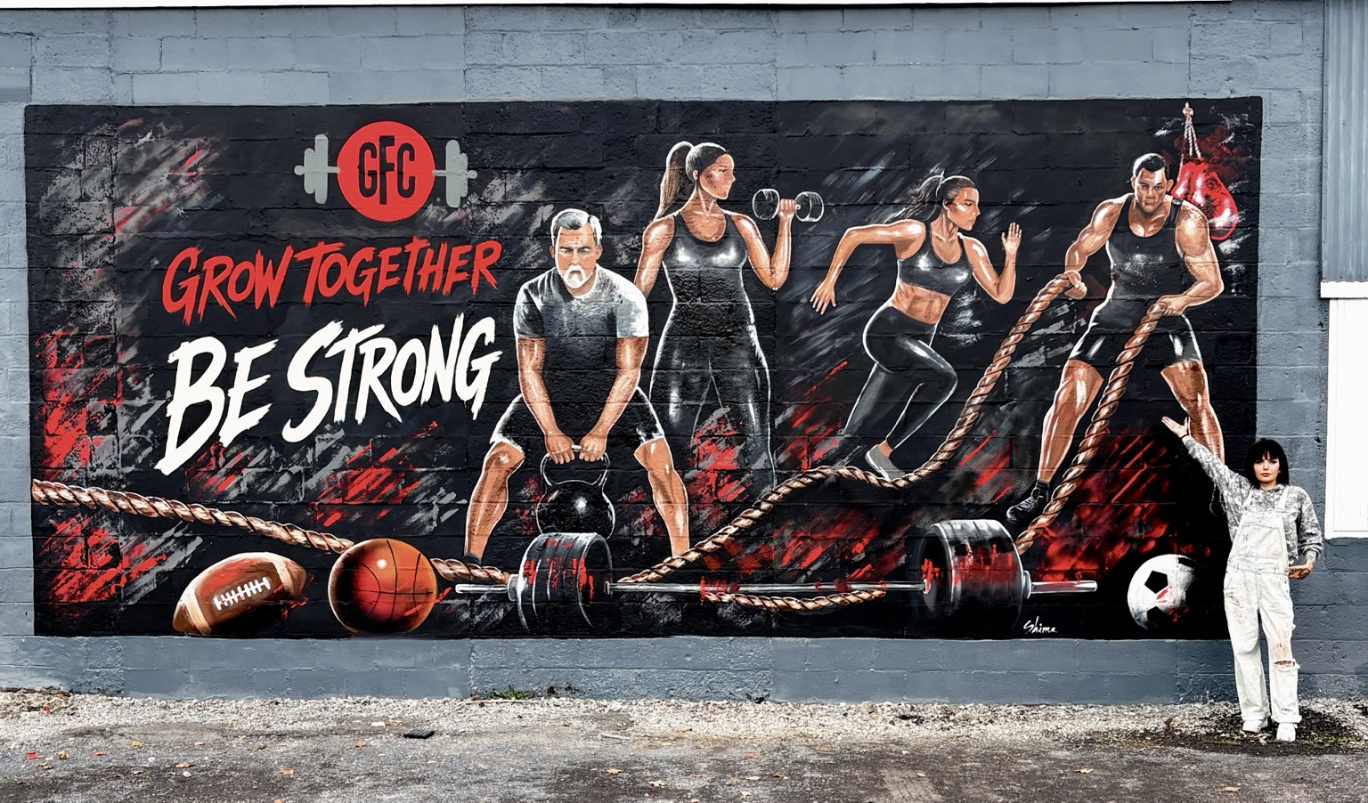 Shima standing beside the completed Grow Together gym mural in Groton, New York